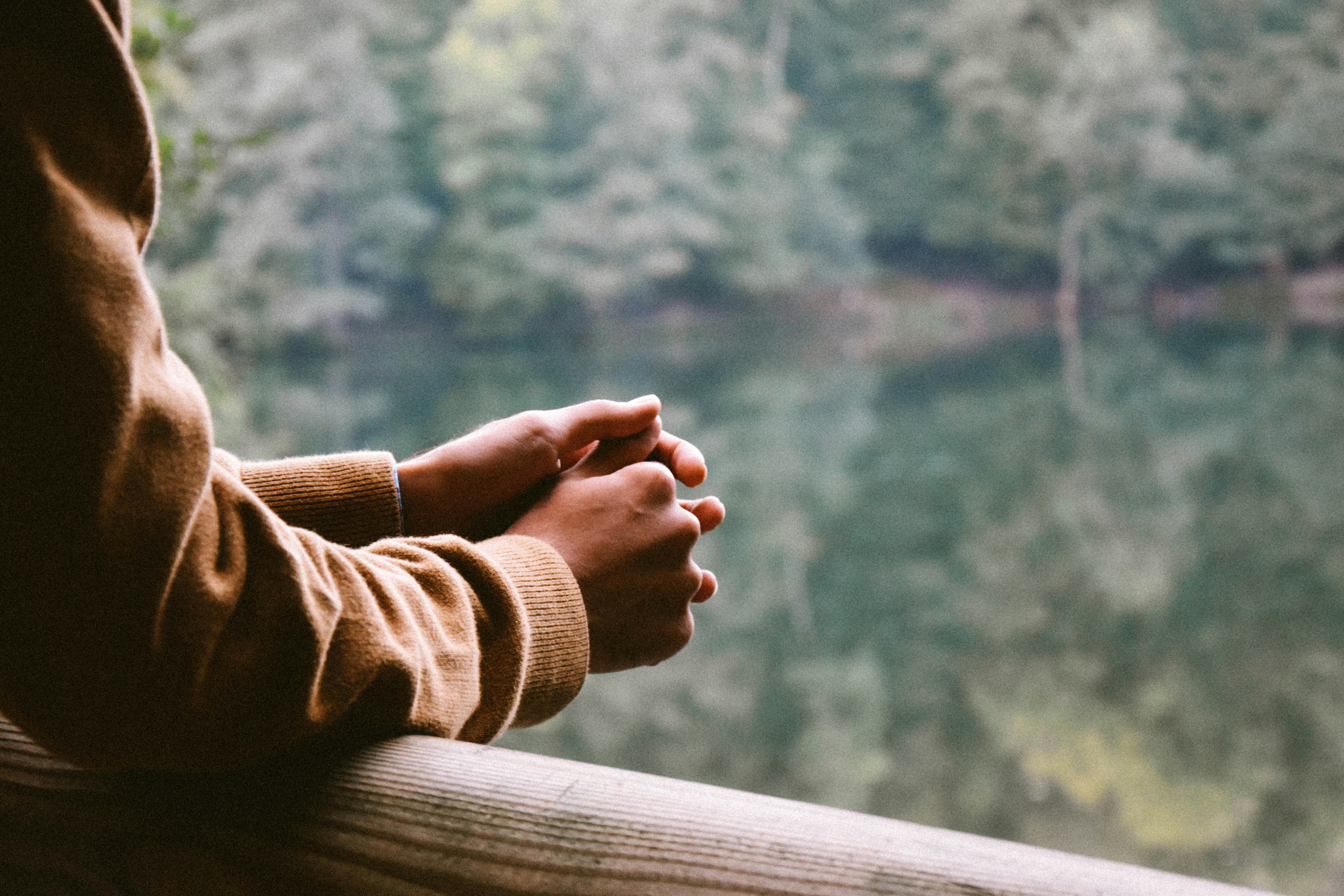 Hands resting together, looking out over water